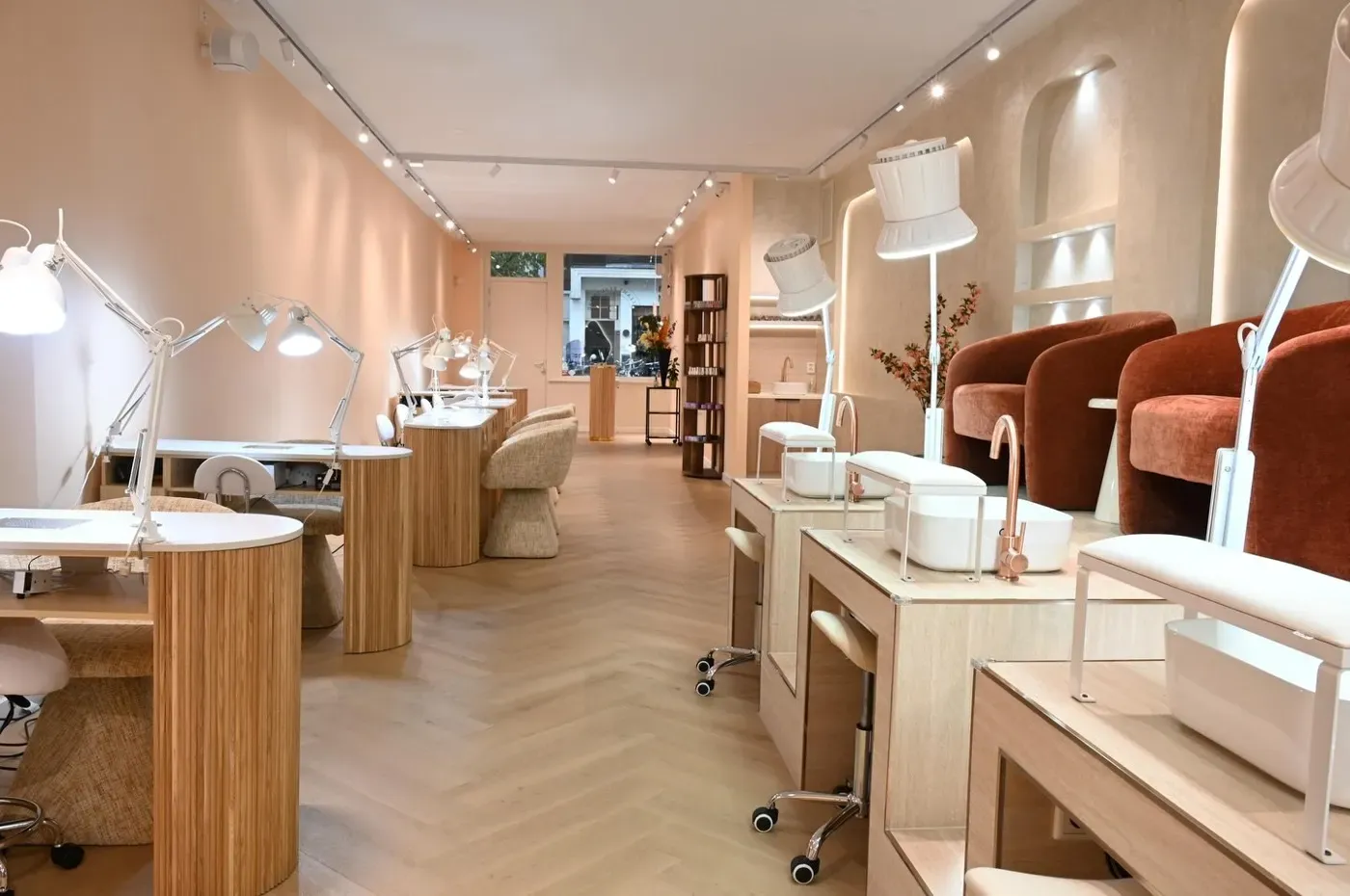 De lange salonruimte met manicuretafels en roestkleurige fluwelen stoelen